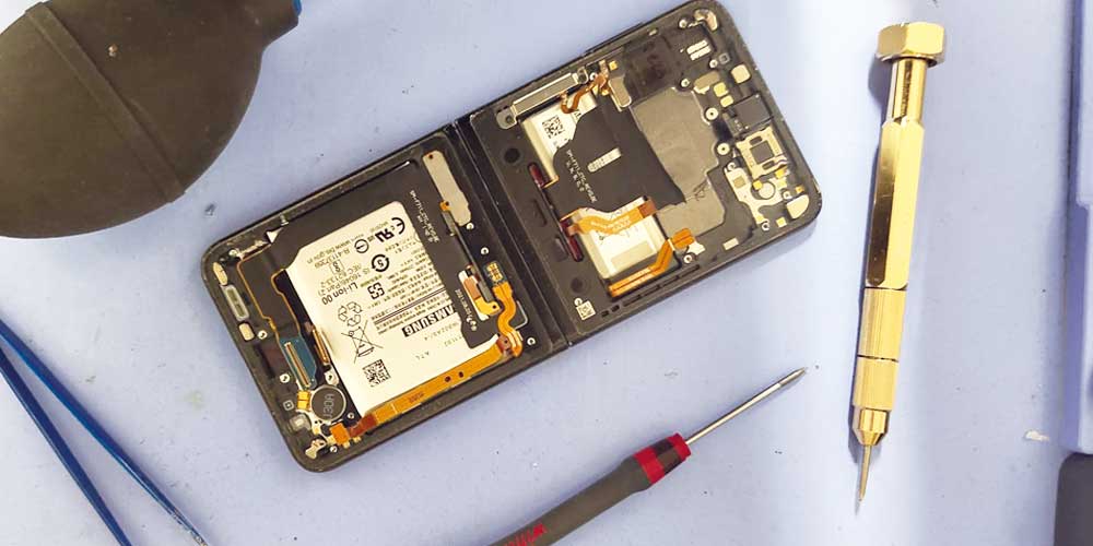 Techniker prüft ein Smartphone bei Ladeproblemen und defekter Ladebuchse in Düsseldorf